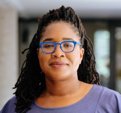 Jasmine McNealy, a black women with long hair and fantastic blue glasses, looks serenely at the camera.196-e1524158885386-300x300.jpg