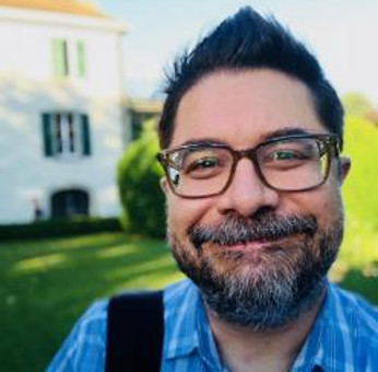 Christopher Bavitz, a oldewhite man with glasses and a beard, smiles at the camera, selfie-style.